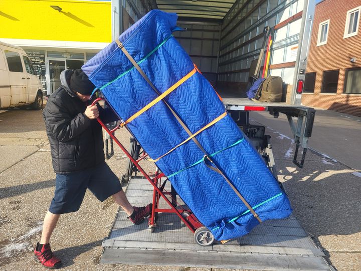 Mover wheeling a blanket-wrapped appliance onto a truck liftgate (pickup and delivery services) by Affordable Moving Solutions of Ohio